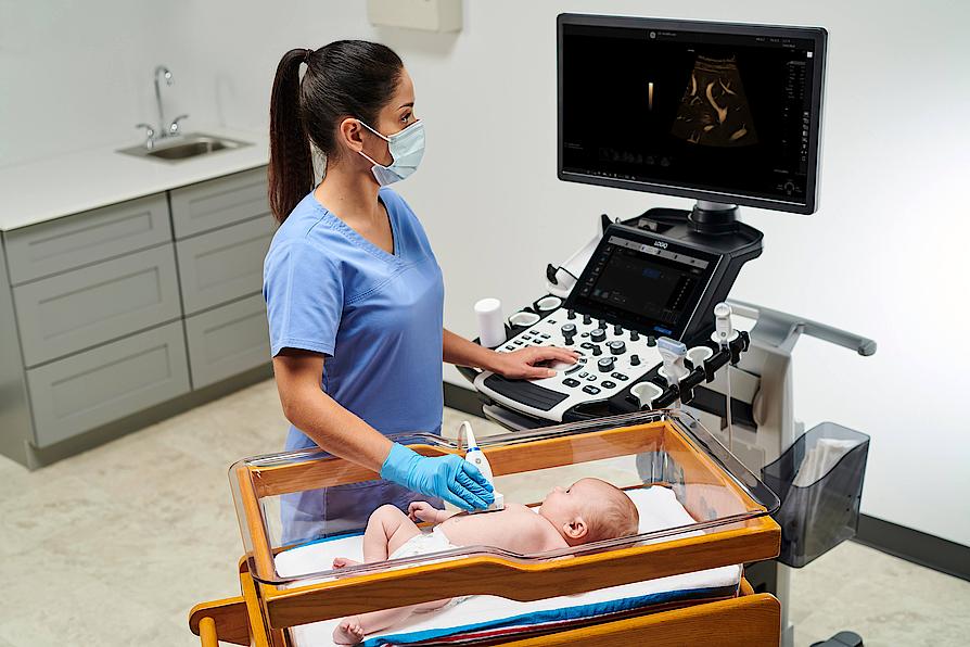 A képen egy orvos látható, amint egy csecsemőn máj-ultrahangvizsgálatot végez.