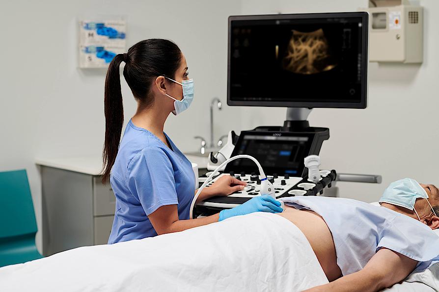Imaginea prezintă un medic ce efectuează un examen ecografic abdominal al unui pacient.