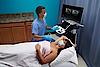 A képen egy orvos látható, amint mammográfiai ultrahangvizsgálatot végez egy női betegen.