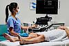 Imaginea prezintă un medic ce efectuează un examen ecografic vascular al unui pacient.