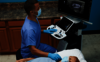 Na zdjęciu widać lekarza przeprowadzającego badanie ultrasonograficzne tarczycy pacjenta.